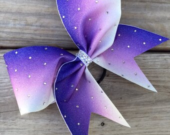May include: A large purple and white ombre cheer bow with silver glitter and rhinestones.