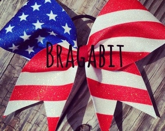 May include: A red, white, and blue glitter cheer bow with the text "BRAGABIT" in black.