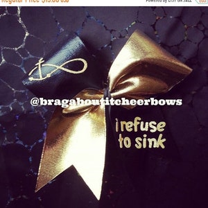 May include: Black and gold cheer bow with an anchor and infinity symbol on one side and the text "I refuse to sink" on the other side.