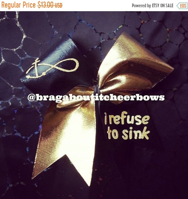 May include: Black and gold cheer bow with an anchor and infinity symbol on one side and the text "I refuse to sink" on the other side.