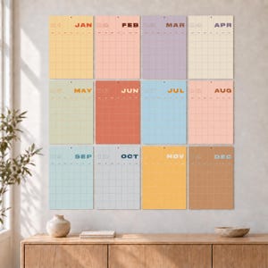 Peut inclure: Un ensemble de calendrier mural composé de douze feuilles rectangulaires, chacune représentant un mois de janvier à décembre. Chaque feuille présente une mise en page en grille, un indicateur numérique du mois et un fond de couleur pastel ou sourde.