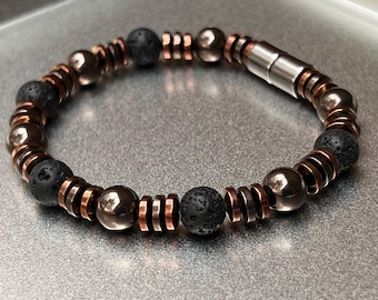 May include: A black and copper beaded bracelet with a magnetic clasp. The bracelet features round black lava rock beads and copper spacer beads.