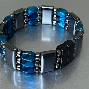 May include: A blue and black magnetic bracelet with a double row of beads. The bracelet is made of hematite and blue glass beads.