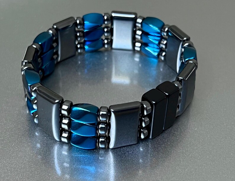 May include: A blue and black magnetic bracelet with a double row of beads. The bracelet is made of hematite and blue glass beads.