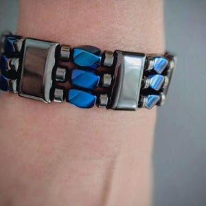 May include: A bracelet with alternating blue and silver beads. The bracelet is made of metal and has a polished finish.