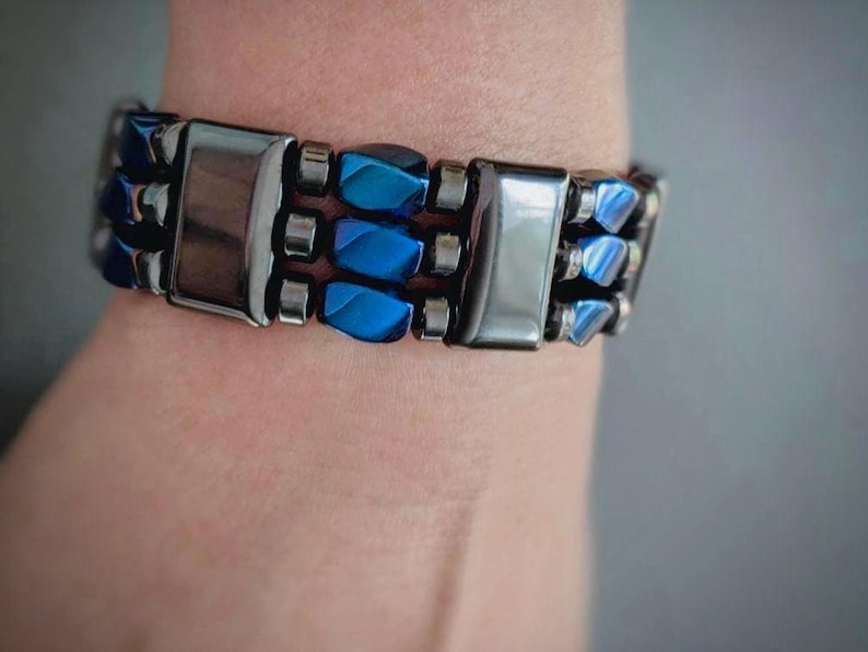 May include: A bracelet with alternating blue and silver beads. The bracelet is made of metal and has a polished finish.