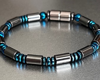 May include: A black and blue magnetic bracelet with a silver magnetic clasp. The bracelet is made of round and rectangular beads.