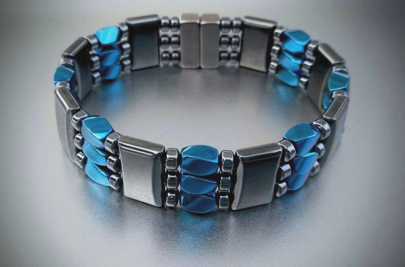 May include: A silver and blue magnetic bracelet with a row of blue rectangular beads and two rows of silver beads.