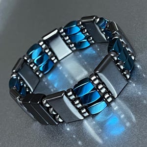 May include: A bracelet made of alternating blue and silver rectangular beads. The bracelet is made of metal and has a polished finish.