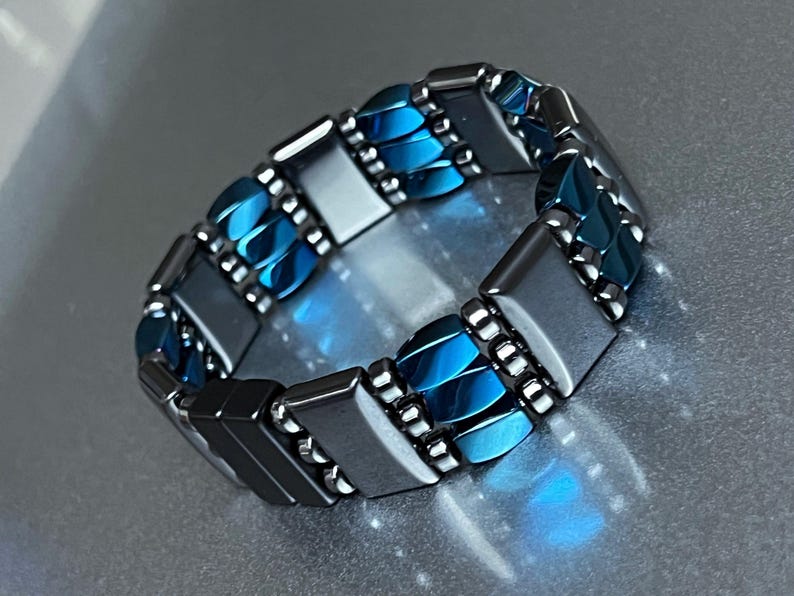 May include: A bracelet made of alternating blue and silver rectangular beads. The bracelet is made of metal and has a polished finish.