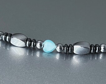 May include: A black and silver beaded bracelet with a light blue heart-shaped bead.