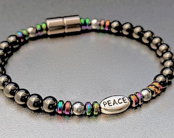 May include: A black hematite beaded bracelet with a silver charm that says "PEACE" and a magnetic clasp. The beads have a rainbow iridescent finish.