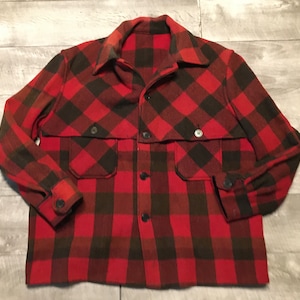 Puede incluir: Una camisa de franela a cuadros rojos y negros con cierre de botones y dos bolsillos grandes. La camisa tiene un corte holgado y está hecha de una tela suave y cómoda.