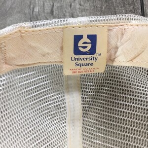 May include: White mesh baseball cap with a brown adjustable strap and a white label that says "University Square" in blue lettering. The label also says "Made in USA" and "One Size Fits All".