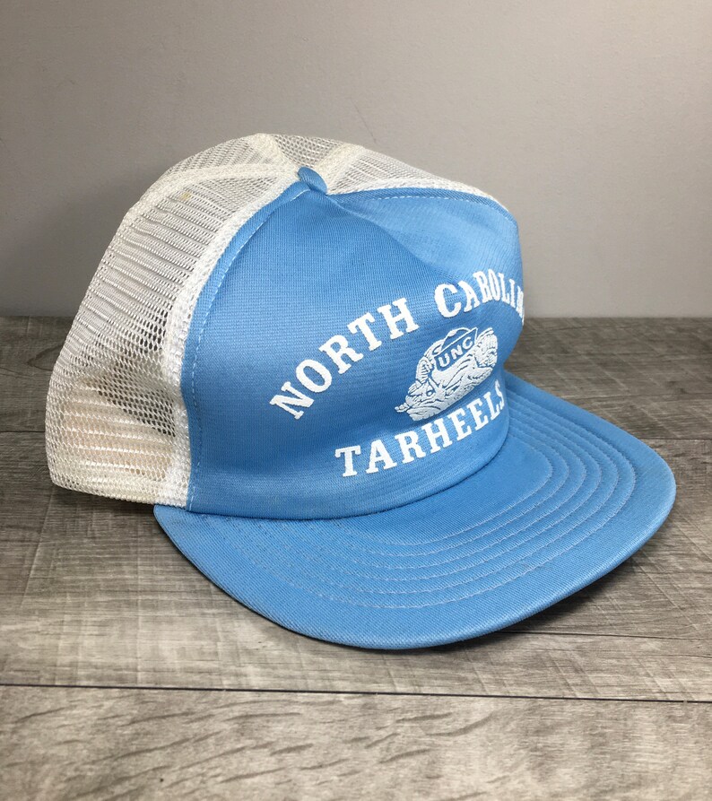 May include: A light blue and white mesh trucker hat with the text "NORTH CAROLINA TARHEELS" and a UNC logo.