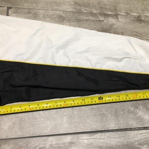May include: Black and white jacket sleeve with a yellow stripe. A yellow measuring tape shows the sleeve is approximately 22 inches long.