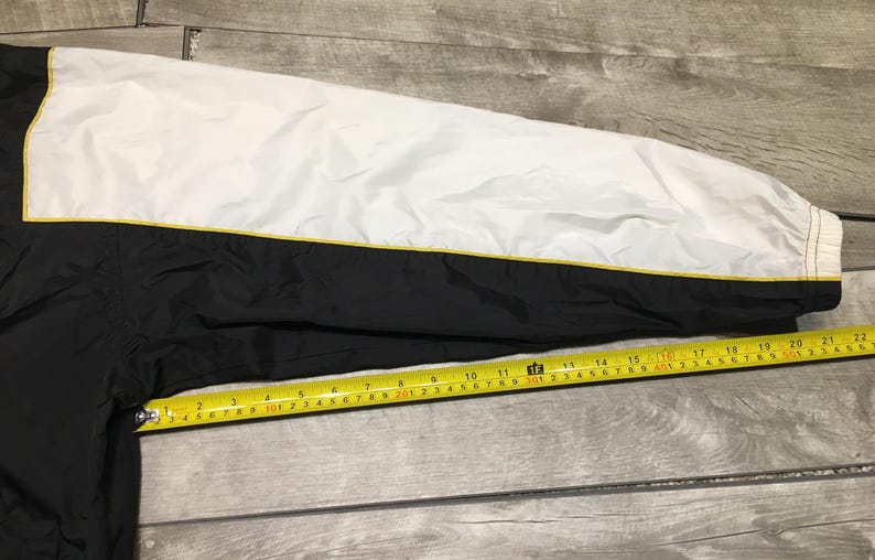 May include: Black and white jacket sleeve with a yellow stripe. A yellow measuring tape shows the sleeve is approximately 22 inches long.