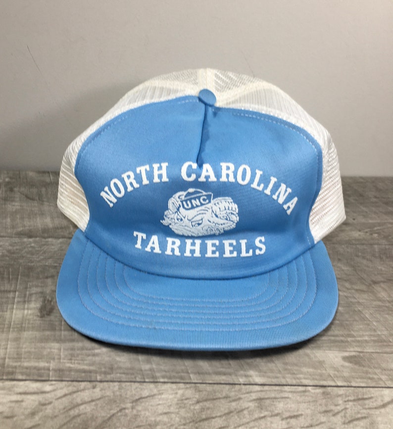 May include: A blue and white trucker hat with the text "NORTH CAROLINA TARHEELS" and a white UNC logo.