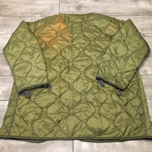 K&ouml;nnte beinhalten: Eine gr&uuml;ne gesteppte Jacke mit Rei&szlig;verschluss und Druckkn&ouml;pfen. Die Jacke hat ein rautenf&ouml;rmiges Steppmuster und ist aus leichtem Material gefertigt.