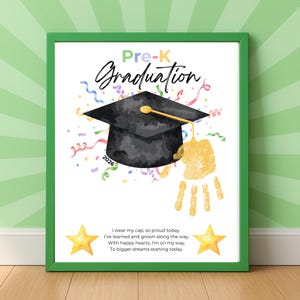 Op de afbeelding: Een ingelijste Pre-K afstudeerprint met een groene rand. De print toont een zwarte afstudeerhoed, een gele handafdruk, kleurrijke confetti en de tekst "Pre-K Graduation 2026". De print bevat ook een gedicht over afstuderen.