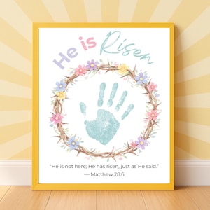 May include: A framed print with the words "He is Risen" in pastel colors. A handprint is centered within a floral and thorn wreath. The quote "He is not here; He has risen, just as He said." is below.