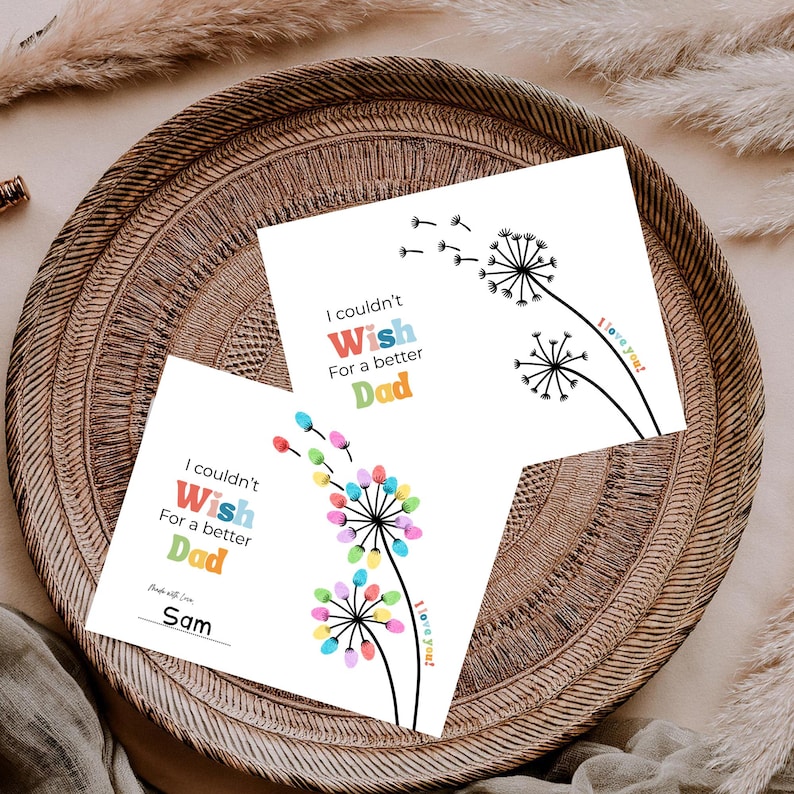 May include: Two white cards with dandelion designs and the text "I couldn't Wish For a better Dad." One card has colorful fingerprint accents and the name "Sam." The other card has a simple black and white design. Both cards say "I love you!"