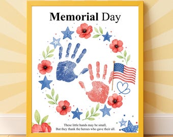 May include: A framed print with a yellow border. The artwork features a wreath of red poppies, blue stars, and green leaves around two handprints, one blue and one red. The American flag and text "Memorial Day" are also included.