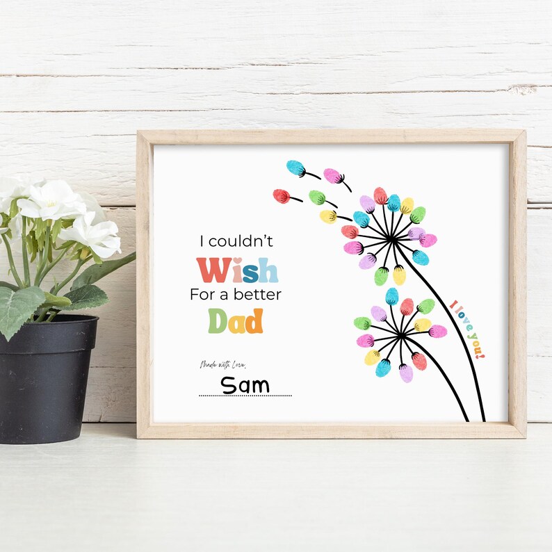 May include: A framed print with the text "I couldn't Wish For a better Dad" in colorful letters. The artwork features dandelion-like designs with colorful accents and the words "I love you!" The print is signed "Sam".