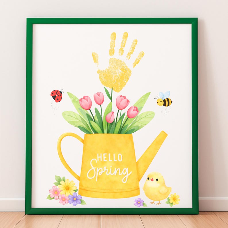 Puede incluir: Una impresi&oacute;n enmarcada con un borde verde. La obra de arte presenta una regadera amarilla llena de tulipanes rosas y hojas verdes. Una huella de mano amarilla est&aacute; encima de la regadera, con una mariquita y una abeja. Las palabras "Hello Spring" est&aacute;n escritas en la regadera.