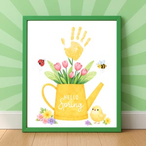 Puede incluir: Una impresi&oacute;n enmarcada con un borde verde presenta una regadera amarilla llena de tulipanes rosas y hojas verdes. Una huella de mano amarilla est&aacute; encima de las flores. Las palabras "Hello Spring" est&aacute;n en la regadera. Una mariquita, una abeja y un pollito tambi&eacute;n est&aacute;n en la imagen.