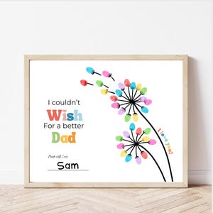 May include: A framed print with a white background features colorful dandelion-like designs made of fingerprints. Text reads "I couldn't Wish For a better Dad" with the name "Sam" below. The words "I love you!" are also included.