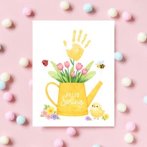 Puede incluir: Una tarjeta blanca con una regadera amarilla llena de tulipanes rosas y hojas verdes. Una huella de mano amarilla est&aacute; encima de las flores. La tarjeta dice "Hello Spring" y tiene una ilustraci&oacute;n de mariquita, abeja y pollito.
