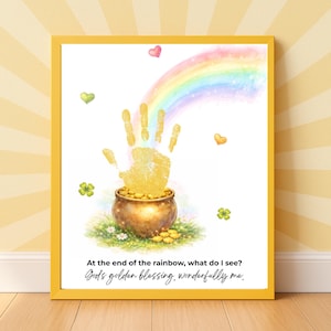 Op de afbeelding: Een ingelijste print met een aquarel regenboog, een gouden handafdruk en een pot goud. De afbeelding bevat harten, klavers en de tekst "At the end of the rainbow, what do I see? God's golden blessing, wonderfully me."