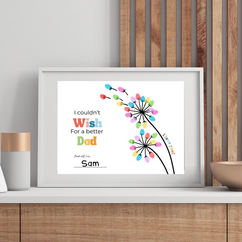 May include: A framed print with the text "I couldn't Wish For a better Dad" and a colorful dandelion design. The dandelion flowers are made of colorful fingerprints. The print is signed "Sam".