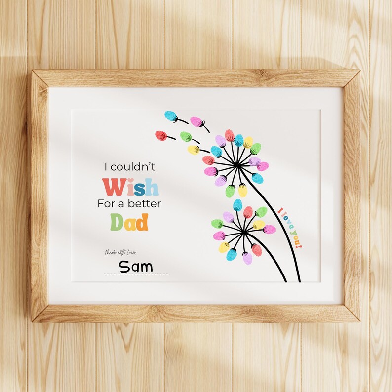 May include: A framed print with a white background and a wooden frame. The print features colorful finger-painted flowers and the text "I couldn't wish for a better Dad." The name "Sam" is written at the bottom, with the words "I love you!" on the right.