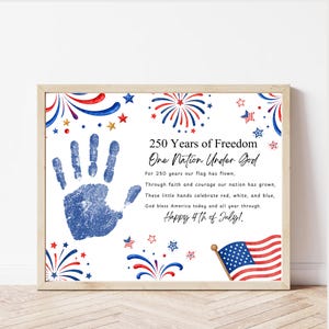 May include: A framed print with patriotic imagery. It features a blue handprint, fireworks, stars, and an American flag. Text includes "250 Years of Freedom" and "Happy 4th of July!" in a wooden frame.