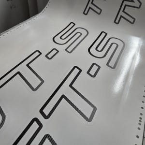 May include: A sheet of white stickers featuring the word "SOFT" repeated in a bold, sans-serif font. The letters are outlined in black with a textured fill. The sheet has perforated edges for easy separation.
