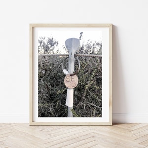 Puede incluir: Primer plano de un poste de metal con una etiqueta redonda marrón unida. La etiqueta tiene las letras "SECO" impresas en ella. El poste está rodeado de follaje verde.