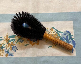 May include: A wooden-handled brush with black bristles. The handle has the text "CHICAGO SERVICE STATION, INC. CAN-O-TEX ACCESSORIES HAMILTON, OHIO AND DAYTON, OHIO" printed on it.