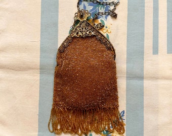 Peut inclure: Un sac à main vintage en perles avec un cadre en métal doré et une bandoulière en chaîne. Le sac est fait de petites perles brunes et a un détail de frange.