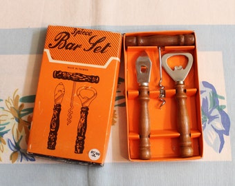 May include: A 3-piece bar set in an orange box with a wood-grain design. The set includes a bottle opener, a corkscrew, and a bottle opener with a wooden handle. The box says "3-piece Bar Set" and "Made in Taiwan".