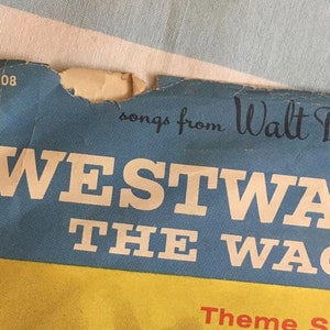 May include: A blue and yellow record album cover with the text "songs from Walt Disney's WESTWARD THE WAGONS" and the number "D308".