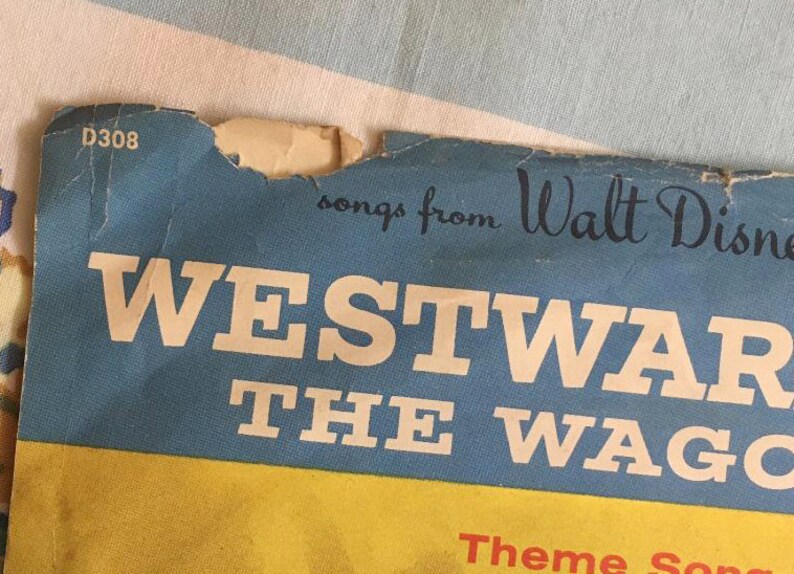 May include: A blue and yellow record album cover with the text "songs from Walt Disney's WESTWARD THE WAGONS" and the number "D308".