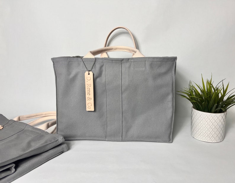 May include: A gray canvas tote bag with a leather handle and a leather tag that says "D. Rene & Co."