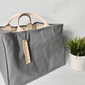 May include: A gray canvas tote bag with leather handles and a leather tag that says "D. Rene & Co."