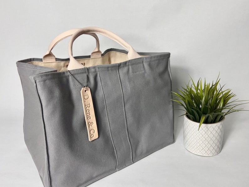 May include: A gray canvas tote bag with leather handles and a leather tag that says "D. Rene & Co."