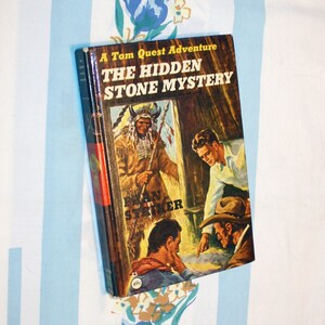 May include: A Tom Quest Adventure book titled "The Hidden Stone Mystery" with a cover featuring a Native American man in a feathered headdress, a man in a cowboy hat, and a map.