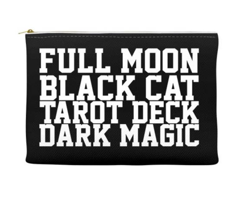 K&ouml;nnte beinhalten: Schwarze Rei&szlig;verschlusstasche mit wei&szlig;em Text, der "Full Moon Black Cat Tarot Deck Dark Magic" lautet.