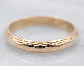 May include: A gold wedding band with a delicate engraved design. The band is smooth and polished, with a slightly rounded profile.