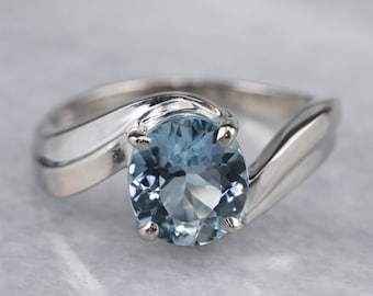 May include: A silver ring with a light blue oval aquamarine gemstone set in a twisted band.